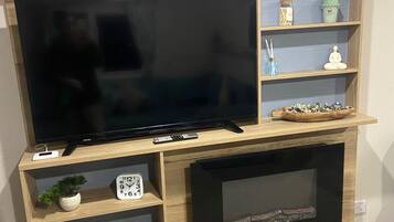 A wooden entertainment center with a flat-screen TV, a fireplace, and shelves with decorative items.