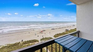 En balkon med udsigt over en strand og hav.