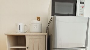 Eine Küchenzeile mit einer Mikrowelle, einem Reiskocher und einem Kühlschrank.