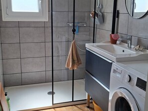 Ein modernes Badezimmer mit Duschabtrennung aus Glas, einem Waschbecken und einer Waschmaschine.
