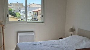 Ett sovrum med en säng, ett fönster, ett element och en lampa.
