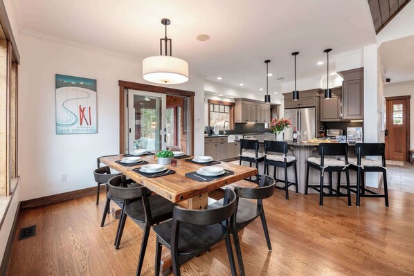 Una cocina moderna con una isla central, mesa de comedor de madera y sillas negras.