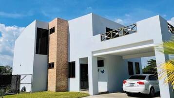 Une maison moderne à deux étages, avec une voiture garée dans l’allée.