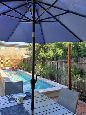 A poolside patio with a table, chairs, and an umbrella. - Cozy 2-bedroom house in marvelous Chico with AC (Chico)