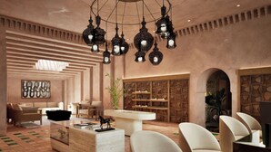 A modern lobby with a reception desk, seating area, decorative lanterns, and a geometric wall design. - Amerruk, Marrakech, Autograph Collection (Marrakech)