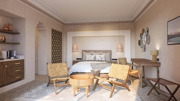 A bedroom with a bed, two chairs, a small table, a coffee machine, and shelves with decorative items. - Amerruk, Marrakech, Autograph Collection (Marrakech)