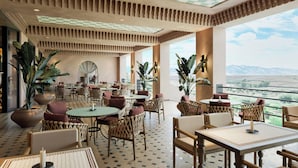 A spacious indoor area with multiple seating arrangements, large potted plants, and a view of the outdoors. - Amerruk, Marrakech, Autograph Collection (Marrakech)