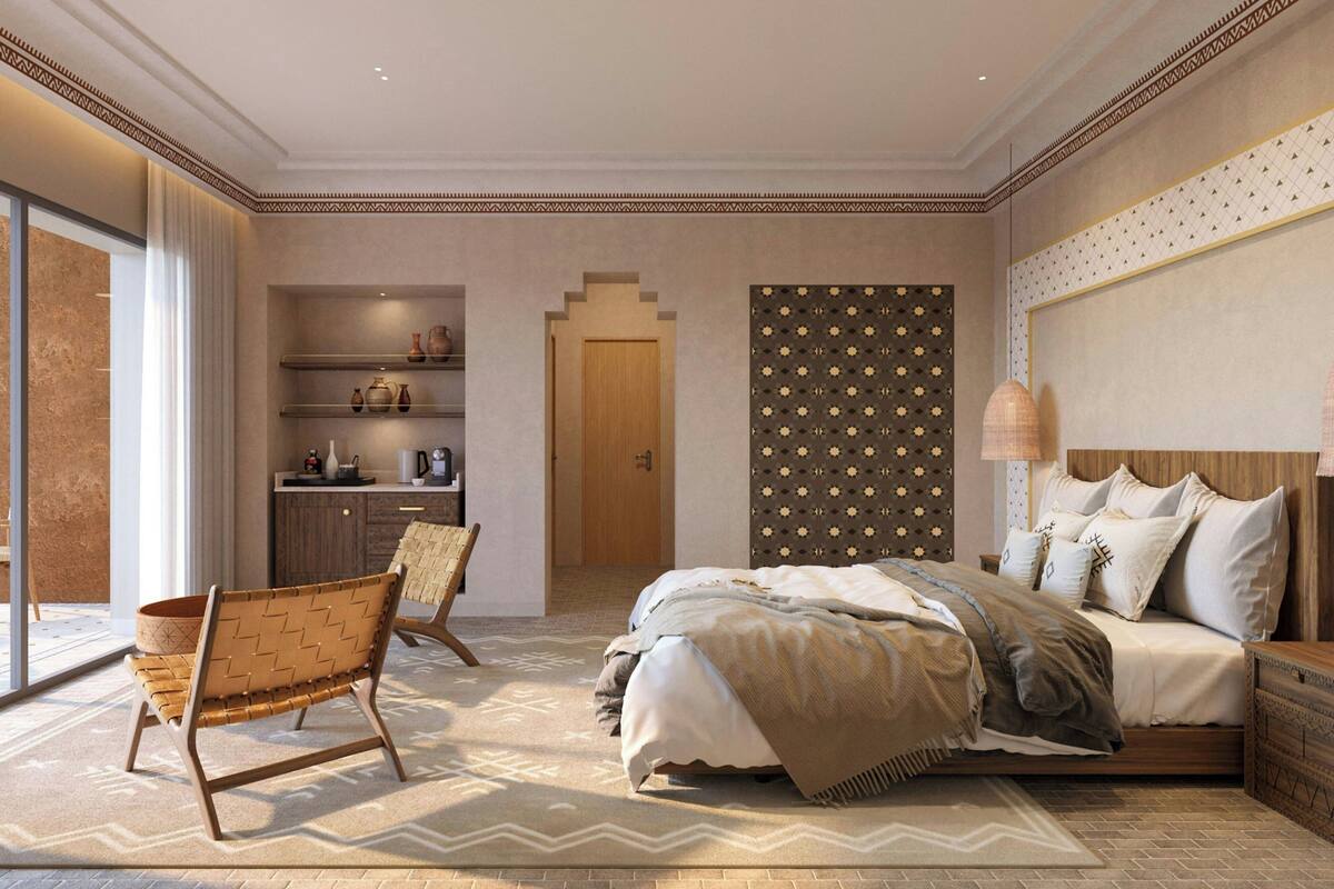 A bedroom with a bed, a chair, a dresser, and a wall with a patterned design.