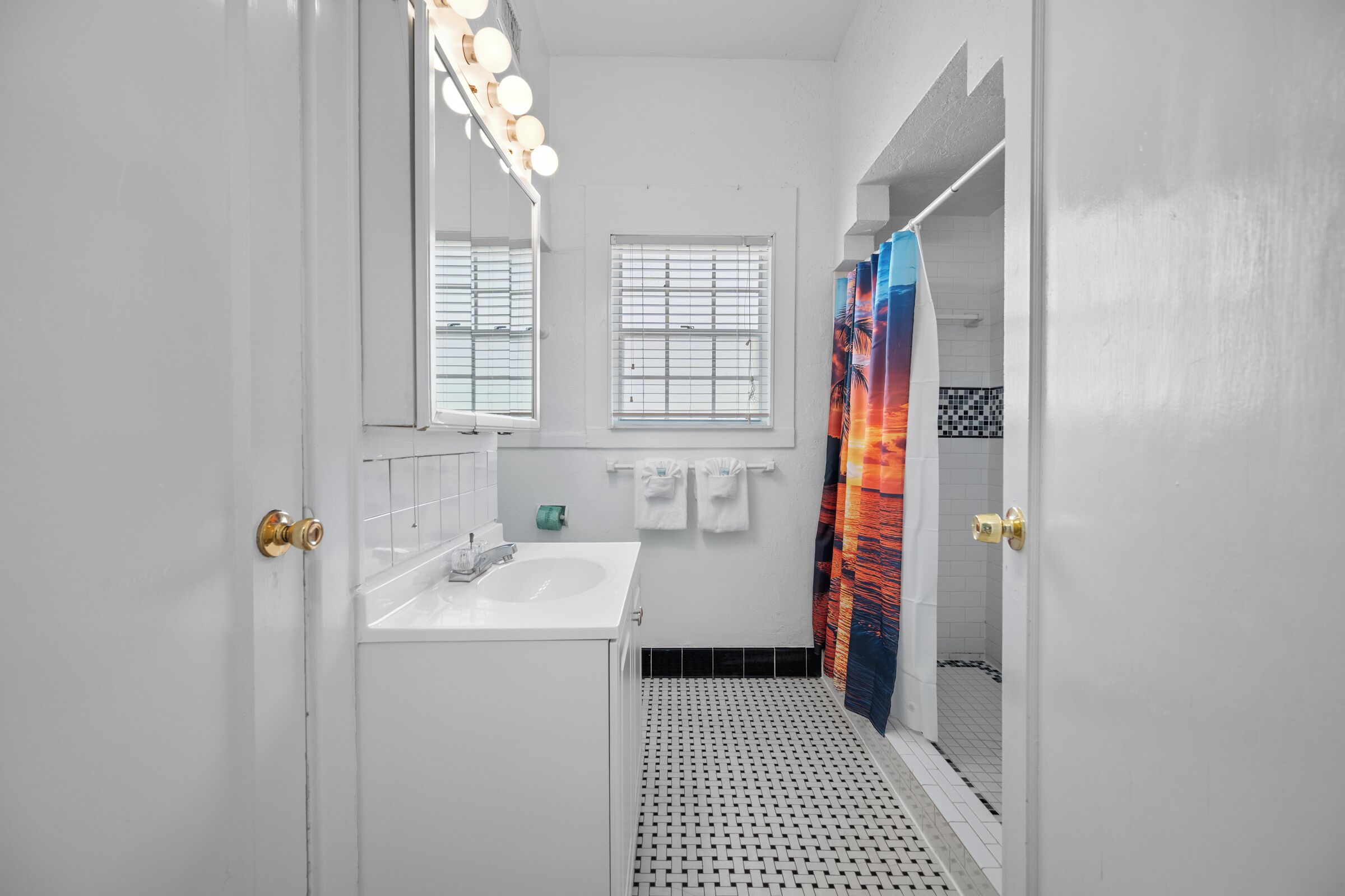 Une salle de bain avec un lavabo blanc, un miroir et un rideau de douche.