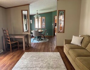 A living room with a sofa, a dining table with chairs, a rug, and a chandelier. - Ultra Spacious & Hosts are Gracious (Oakland)