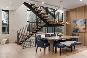 A modern interior with a staircase, dining table, chairs, and a painting on the wall. - Abode at Sky View, rooftop hot tub, walk to town (Jackson)