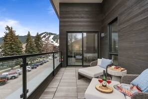 A balcony with a view of a snowy mountain, a car parked outside, and a table with a bottle and glasses. - Abode at Sky View, rooftop hot tub, walk to town, stunning views (Jackson)