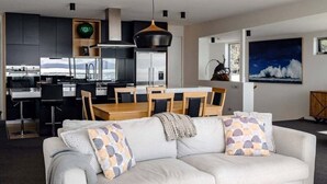 A modern living room with a sofa, dining table, and kitchen area with cabinets and appliances.