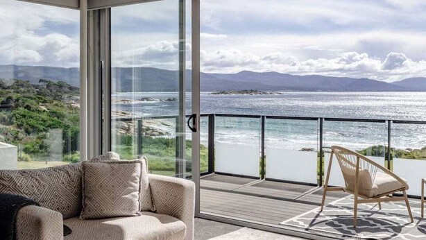 A balcony with a view of the sea, a sofa, and a chair.