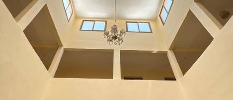 A high-ceilinged atrium with skylights, a chandelier, and a marble column.