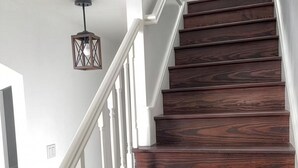 Una escalera de madera con barandillas blancas y un colgante de luz.