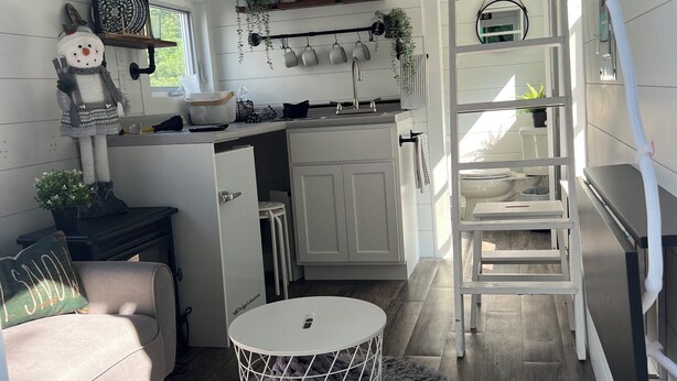 Una cucina compatta con mobili bianchi, un lavello e un piccolo angolo ristoro.