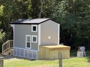 A small, single-story building with a sloped roof, a wooden deck, and a fenced yard. - Rare Find: Unique Stonington Tiny House on Private Horse Farm & Kennel (Stonington)