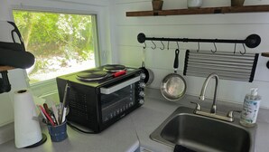 Una cucina compatta con fornello, lavello e finestra vista sul verde.