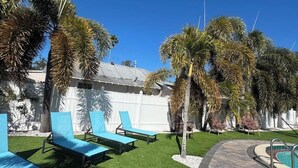 A poolside area with lounge chairs, palm trees, and a pool. - Sunny Poolside Retreat | Near Beach & Dining (Clearwater)