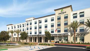 A hotel with a modern facade, multiple windows, and a parking lot with designated spaces.