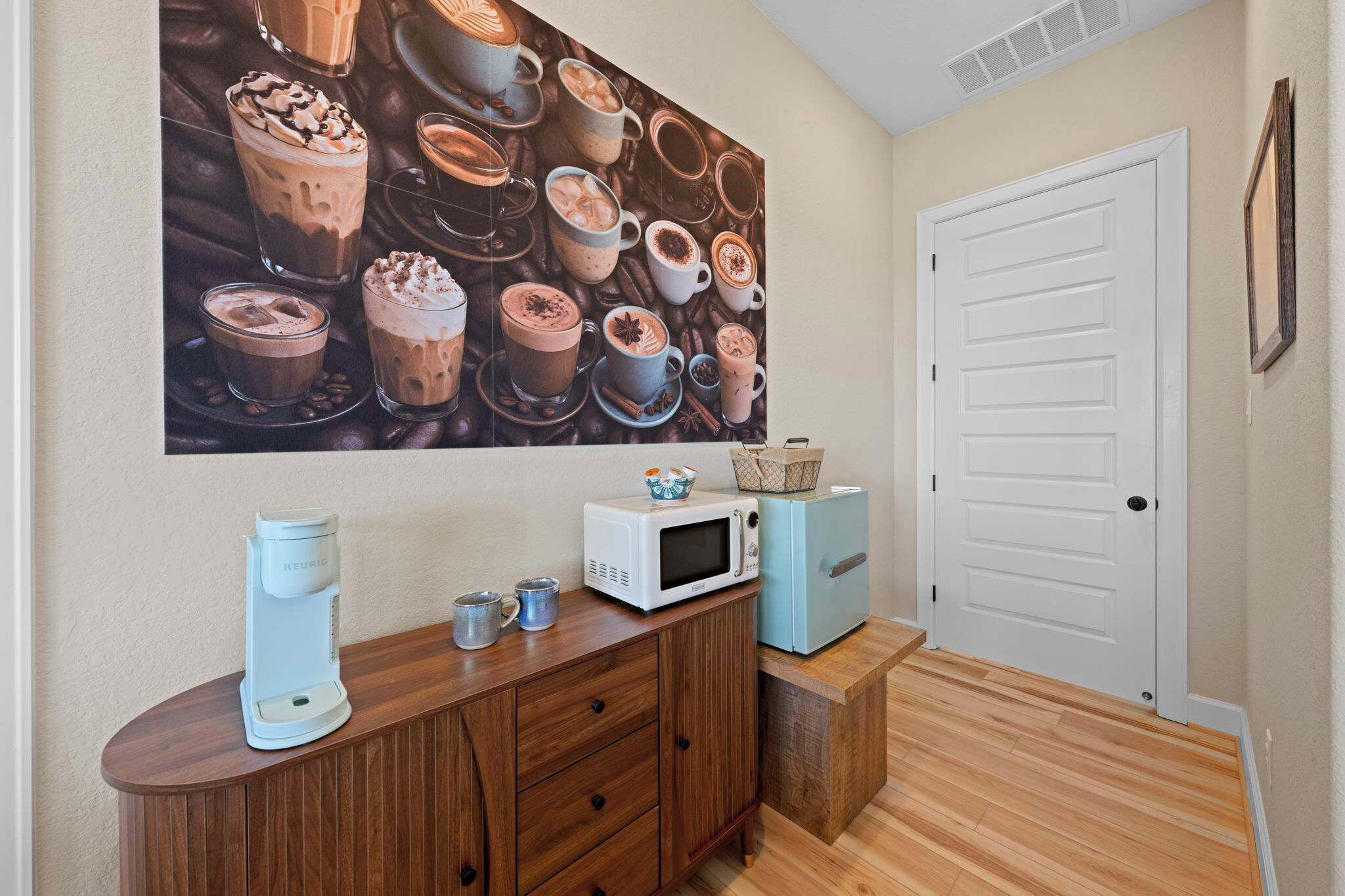 A room with a coffee maker, microwave, and a door.