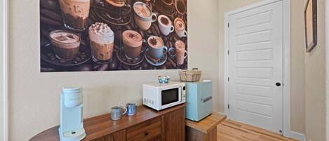 A room with a coffee maker, microwave, and a door.