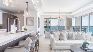 Ein modernes Wohnzimmer mit einem weißen Sofa, Korbstühlen und einem Essbereich mit einem Glastisch.
