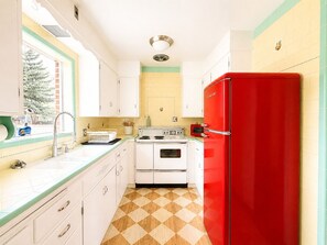 A kitchen with white cabinets, a red refrigerator, a stove, and a window with a view of trees. - Family-Friendly 4BR Game Room & Near Downtown (Idaho Falls)