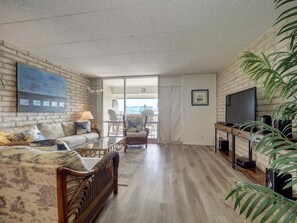 A living room with a sofa, a television, a coffee table, and a plant. - Relax at Coral Cay #214, a spacious 2BR condo in Port Aransas, near the beach. (Port Aransas)
