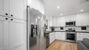 Una cocina moderna con armarios blancos, electrodomésticos de acero inoxidable, horno empotrado y microondas.