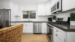 A modern kitchen with white cabinets, stainless steel appliances, and a wooden floor. - Large Newport Beach Home Walk to the Beach (Newport Beach)