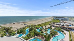A resort with multiple swimming pools, a beach, and a construction crane. - Emerald Suite 607 ~ Luxury 3BR Oceanfront + Full Resort Amenities Included (Galveston)
