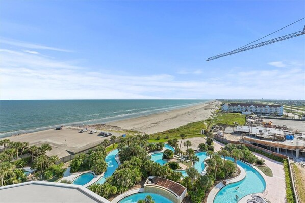 Un resort con varias piscinas, una playa y una grúa de construcción.