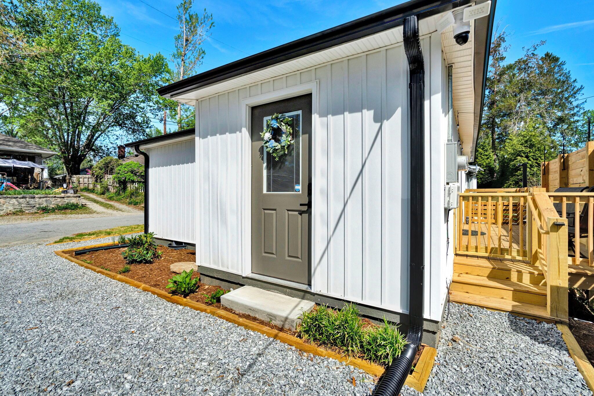 A small, single-story building with a front door, a small porch, and a gravel driveway.