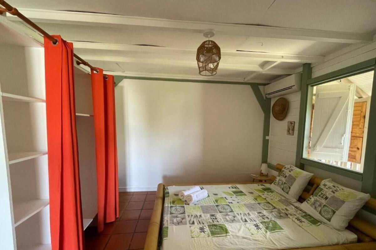 A bedroom with a bed, a window, a shelf, and a door.