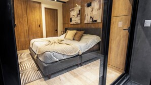 Een moderne slaapkamer met een bed, een houten garderobe en abstracte wanddecoratie.