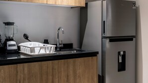 Een keuken met houten kastjes, een roestvrijstalen koelkast, een gootsteen en een blender.