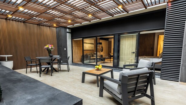Een terras met een tafel, stoelen en een bank.