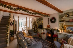 Una sala de estar acogedora con chimenea, escalera y adornos navideños.