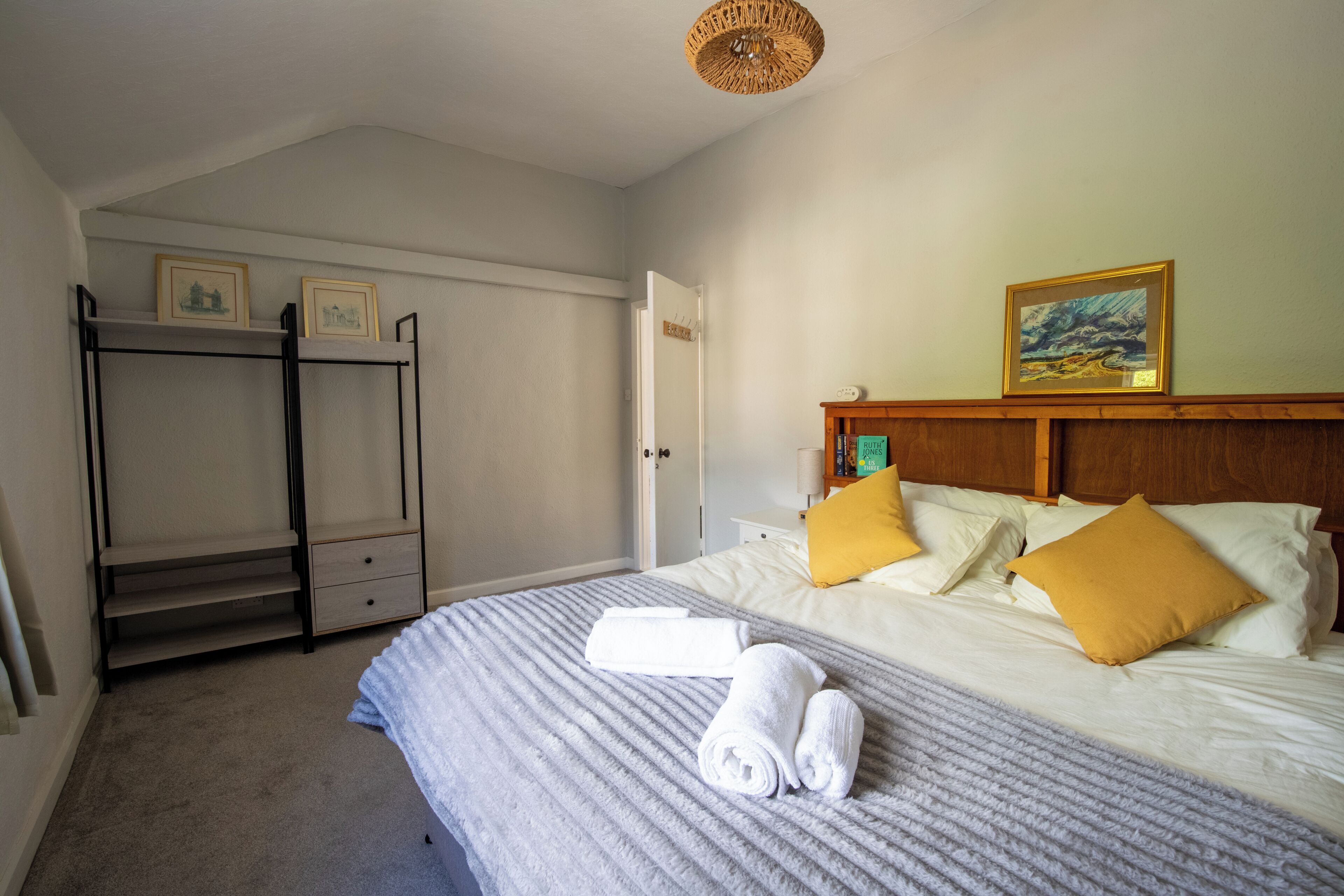 A bedroom with a bed, two side tables, a wardrobe, and a door.