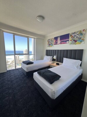 A hotel room with two beds, a large window with a city view, and artwork on the wall. - `Beside Still Waters` Luxury Escape (Surfers Paradise)