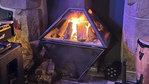 Uma lareira de pedra com caixa hexagonal, um conjunto de bateria e um sistema de som.