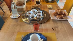 Mesa posta para dois com pratos, xícaras e diversos alimentos.