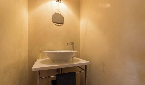 Ein Badezimmer mit einem weißen Waschbecken, einem Spiegel und einem Handtuchhalter.
