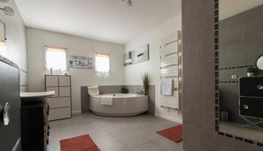 Ein modernes Badezimmer mit einer freistehenden Badewanne, einem Waschtisch mit Spiegel und einer Duschkabine.