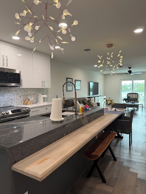 A modern kitchen with a large island, stainless steel appliances, and pendant lighting.