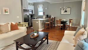 Een woonkamer met een bank, een salontafel en een eethoek met stoelen en een tafel.