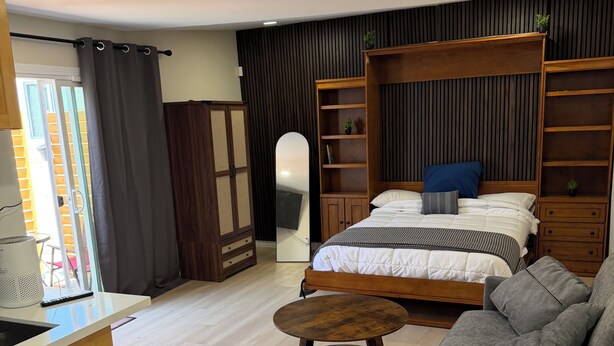 Un dormitorio moderno con cama, sofá, mesa de madera y armario.