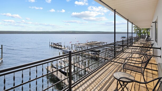 Un balcón con vista al agua, barandillas de metal y mobiliario exterior.